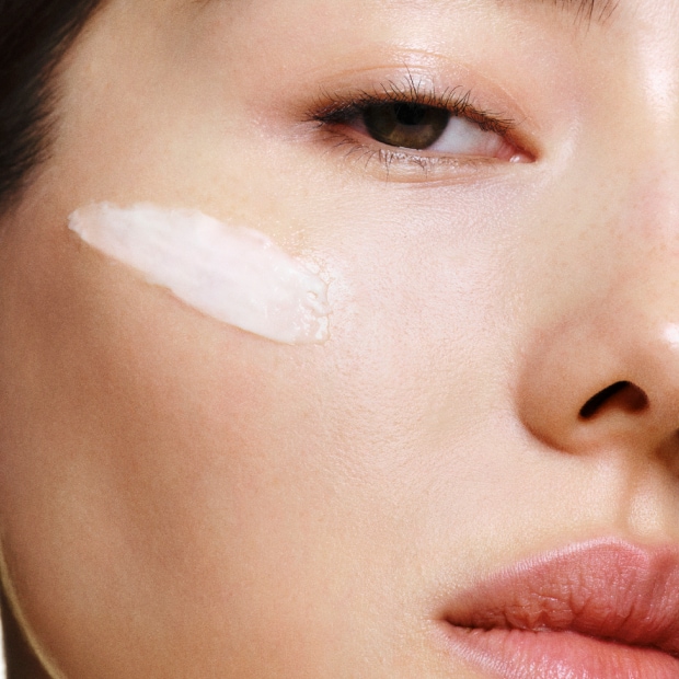 Model applying Skin Long-Wear Weightless Foundation to skin with a foundation brush